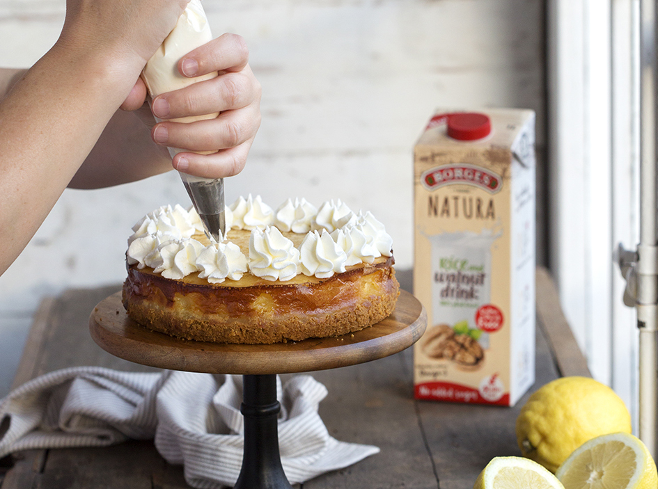 Lemon tart on a cake stand being decorated with a pastry bag