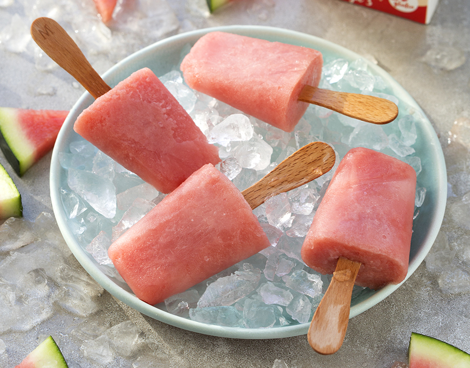 Polos o helados de sandía caseros servidos en un bol con cubitos de hielo