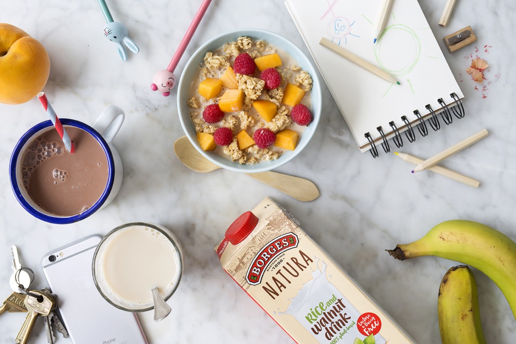 Veggie breakfast made of a bowl of cereals with some fruits and cup of Borges vegetable drink