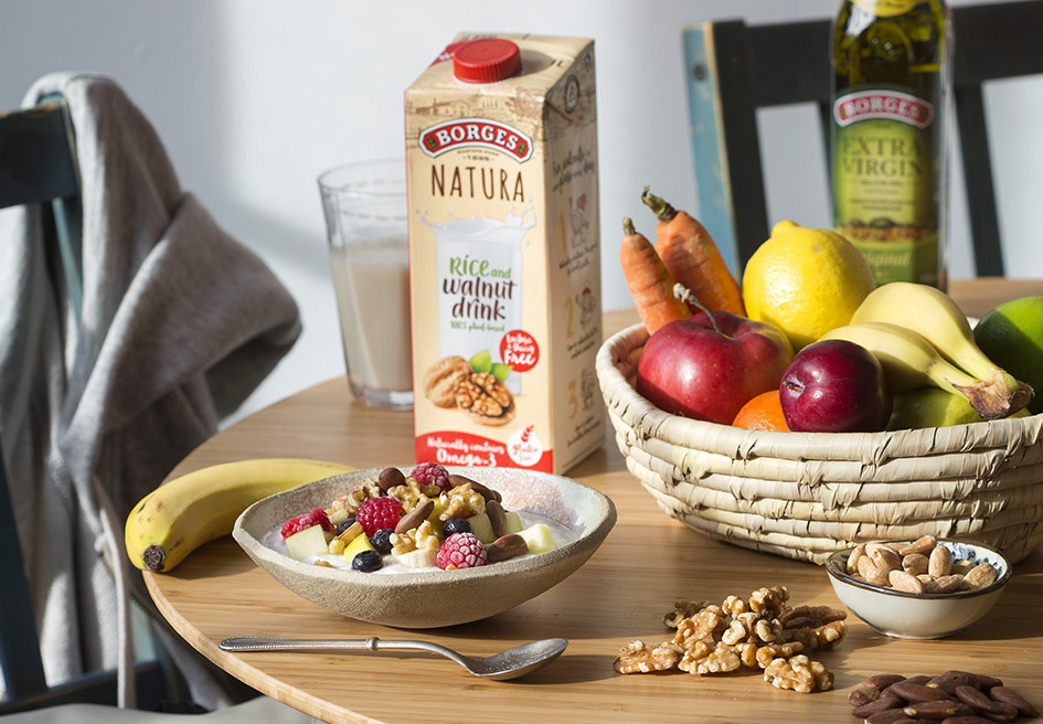 Table with fruits, vegetable drink, olive oil and nuts, ingredients that slow down aging