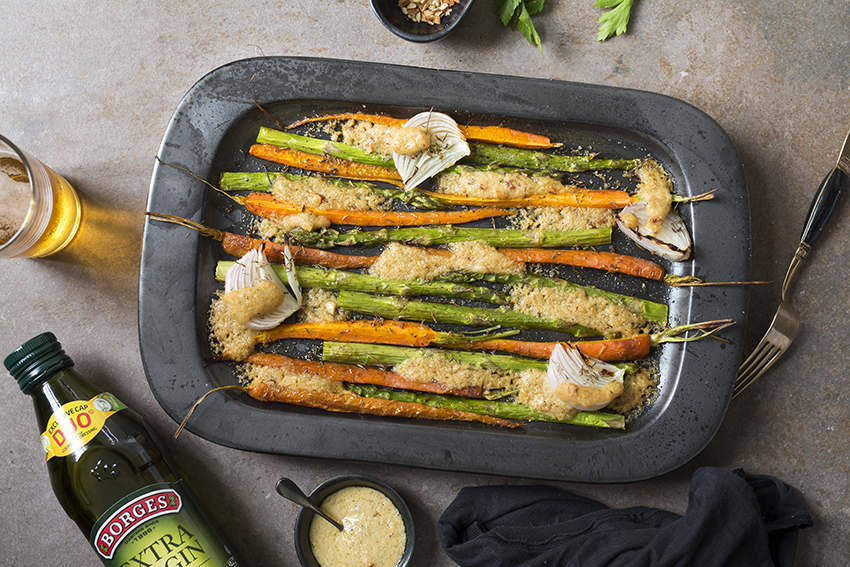 Zanahorias asadas con espárragos y almendras servidas en una bandeja de horno con aceite de oliva virgen extra de Borges