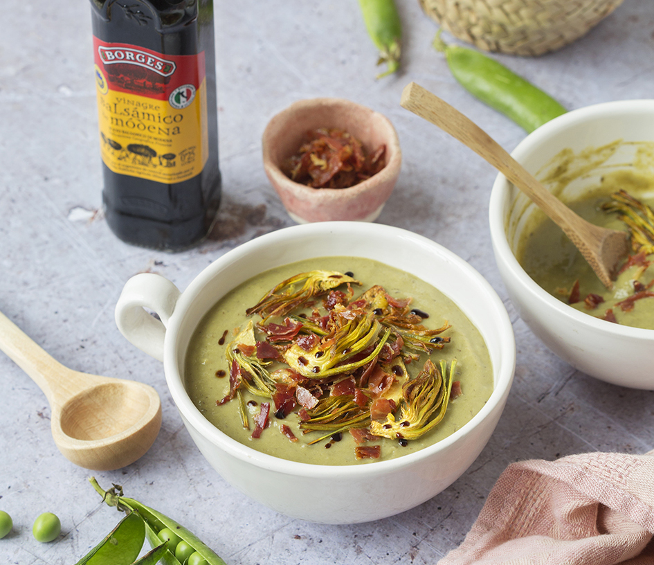 Crema de verduras con guisantes, alcachofas y espárragos servida en un bol