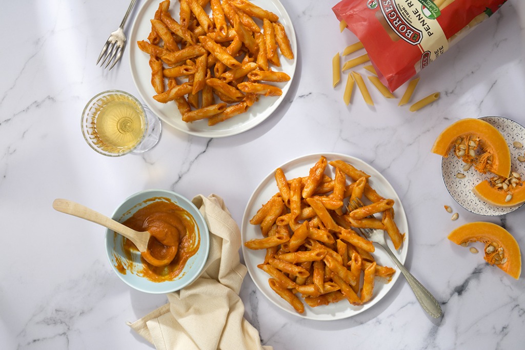 Two dishes of penne rigate pasta with tomato sauce and sliced pumpkin