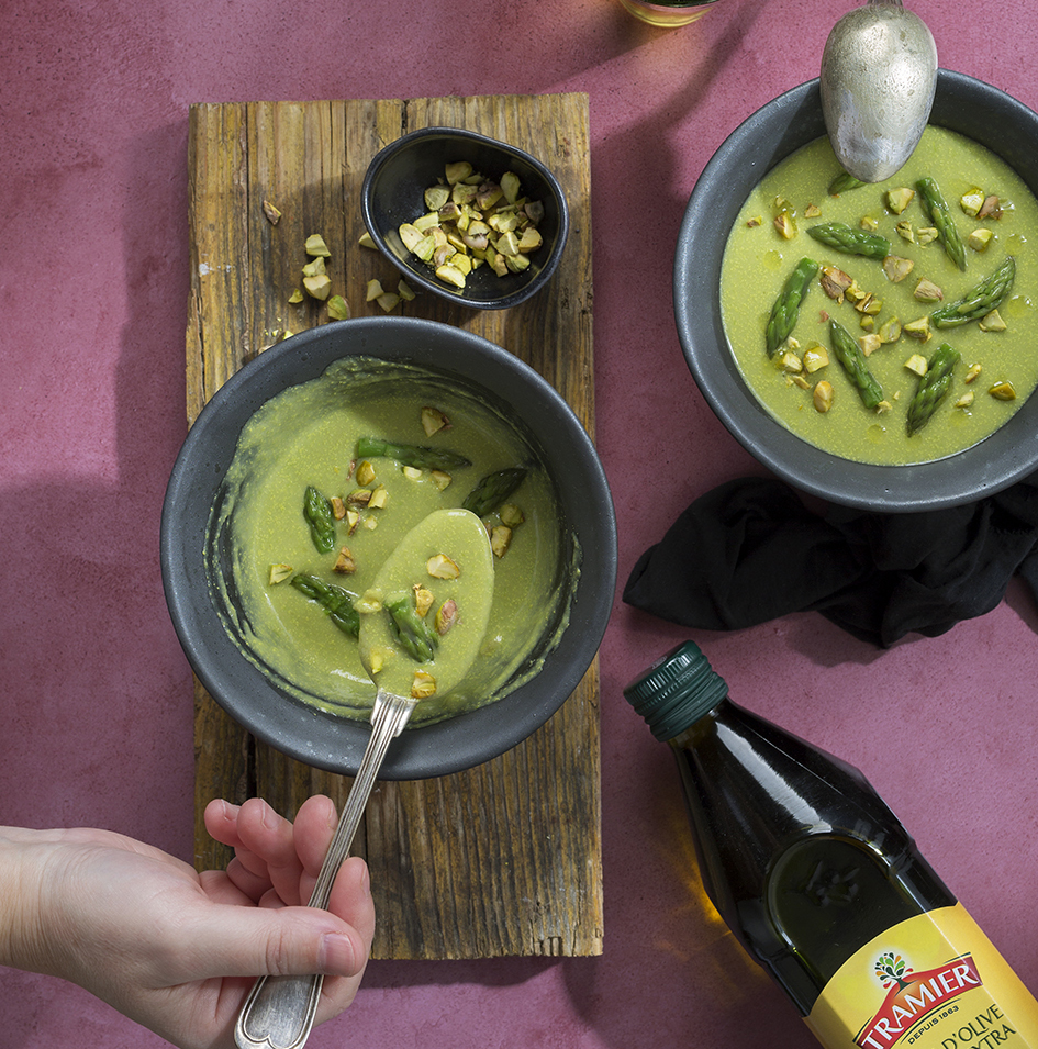 Dairy-free vegetable soup served in a bowl with asparagus and pistachios