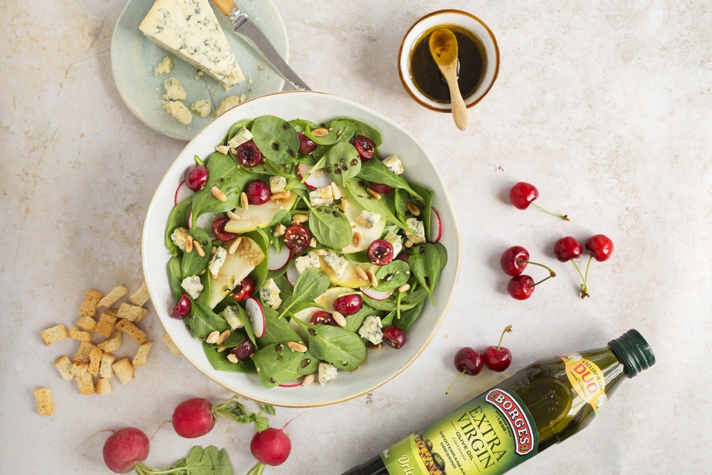 Plato de ensalada de espinacas con cerezas, frutos secos y queso con vinagreta
