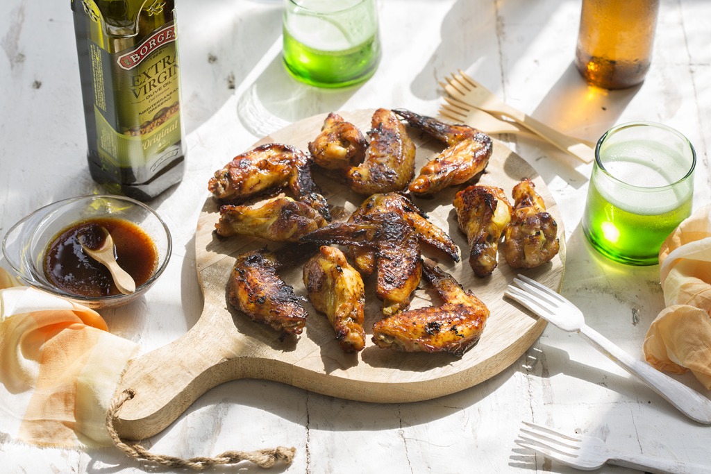 Alitas de pollo con miel servidas en una tabla de cortar de madera