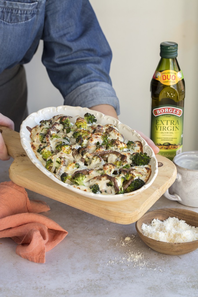 Beef and broccoli recipe served in a white dish next to a Borges olive oil bottle
