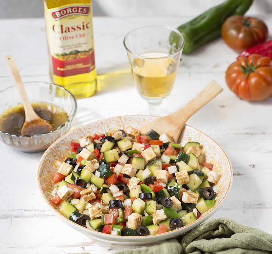 Bowl of cucumber salad with black olives and cheese
