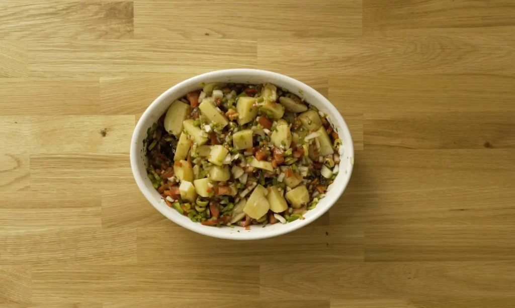 Ensalada de patatas, olivas y verduras servida en una fuente ovalada