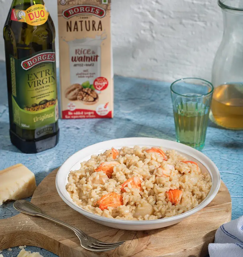 Lobster risotto served in a dish next to olive oil bottle and rice and walnut milk tetra-brick