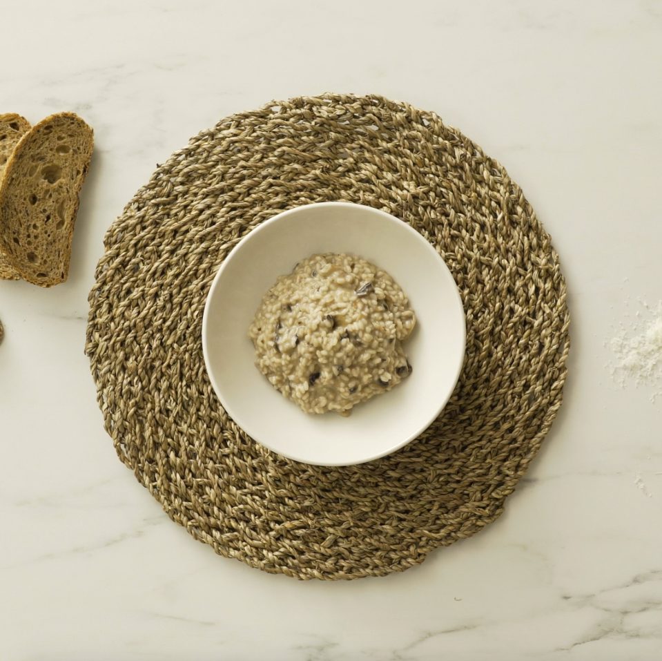 Mushroom risotto recipe served in a soup plate on a round fiber place mat