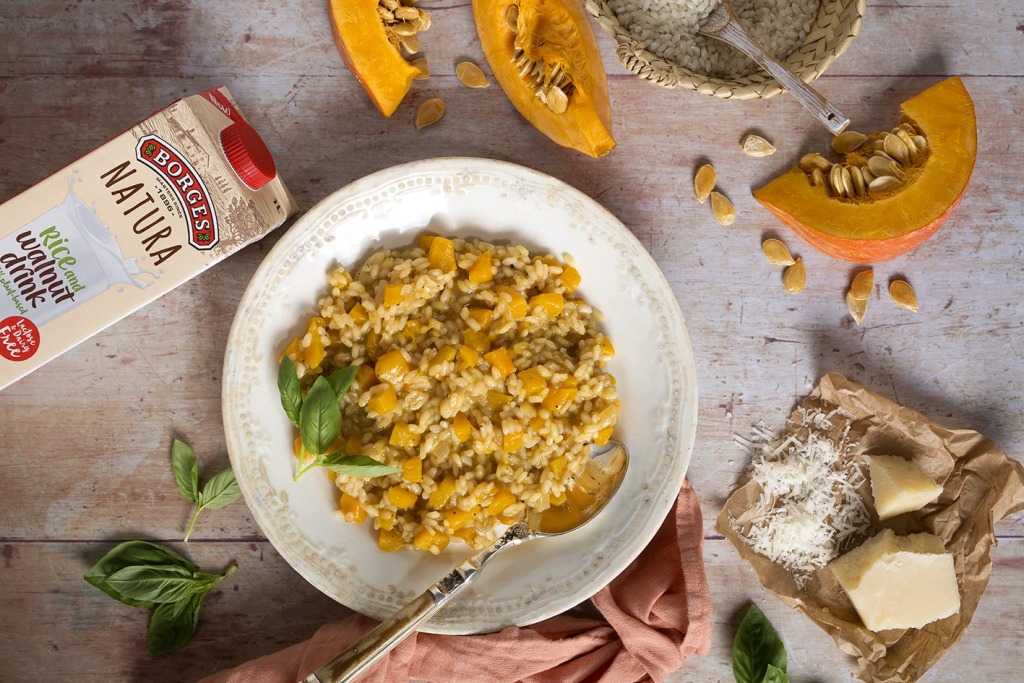 Pumkin risotto served in a porcelain plate with basil leaves