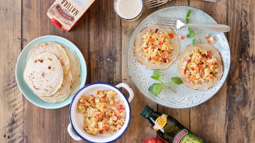 Tacos para el desayuno servidos en un plato junto con fajitas, relleno y otros ingredientes